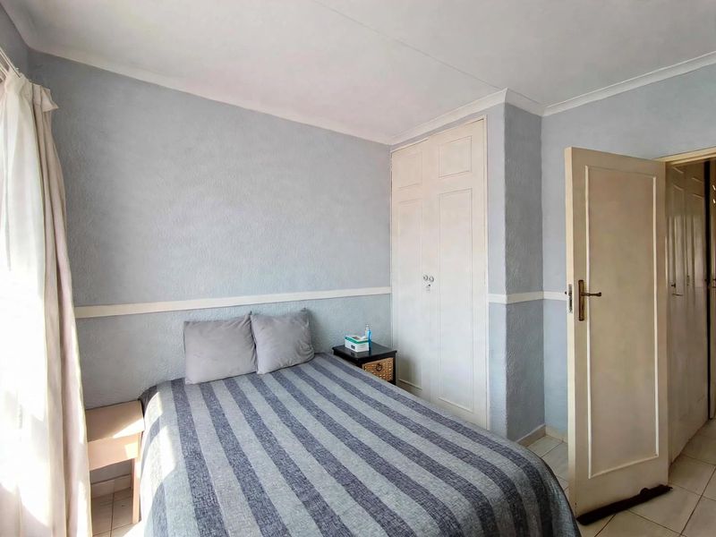 A functional bedroom featuring built-in wardrobes, tiled flooring, and coved ceilings, offering a neutral base for potential interior updates.