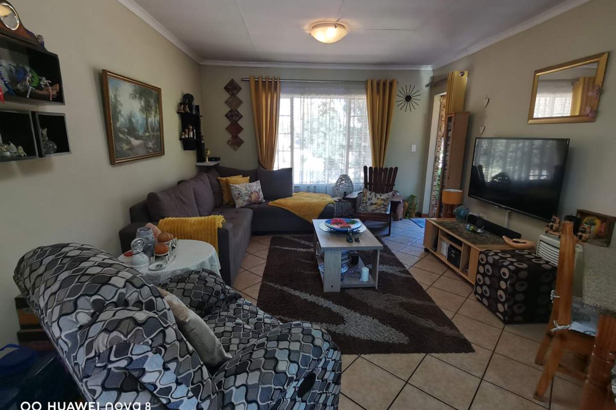 A comfortable living room featuring tiled flooring and a large window, providing a functional and lived-in space for relaxation.