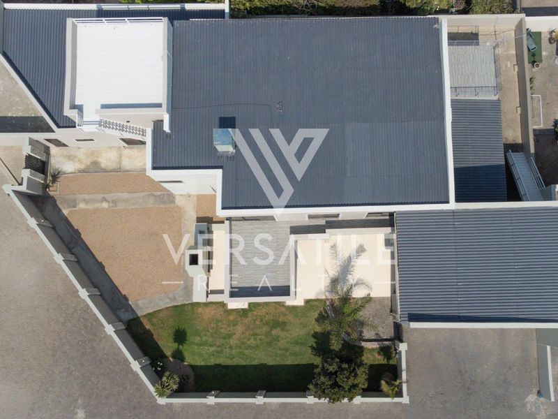 Aerial view of the property showing the roof structure, garden area, paved driveway, and boundary walls.