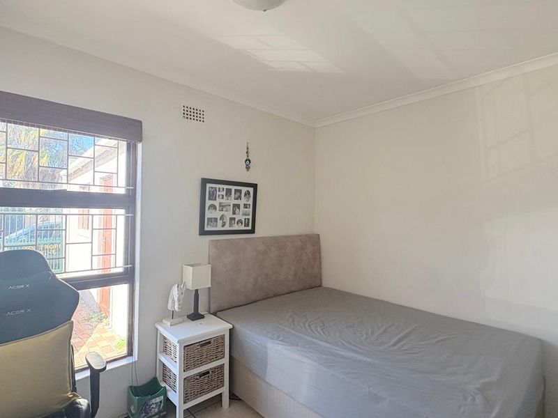 A functional bedroom featuring a window with security bars and neutral wall finishes, providing a comfortable and secure living space.