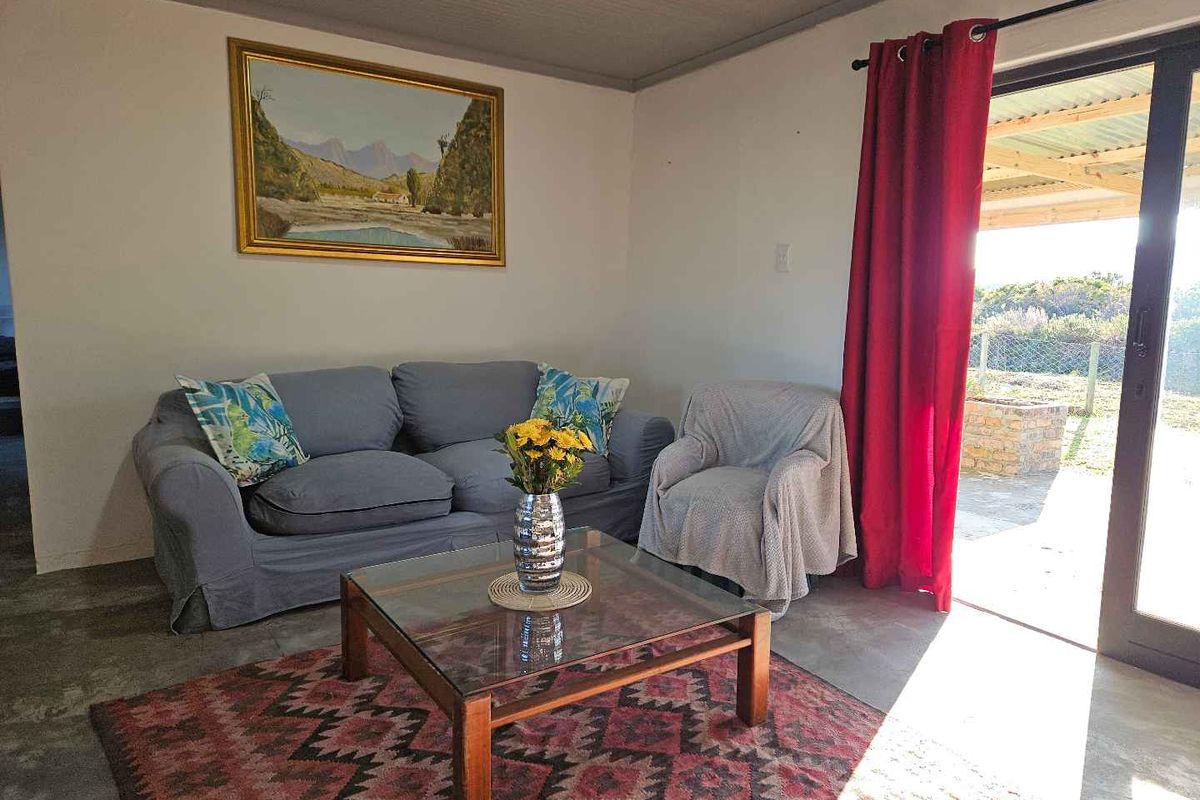 A comfortable living room featuring concrete flooring and large sliding glass doors that provide direct access to an outdoor patio area.