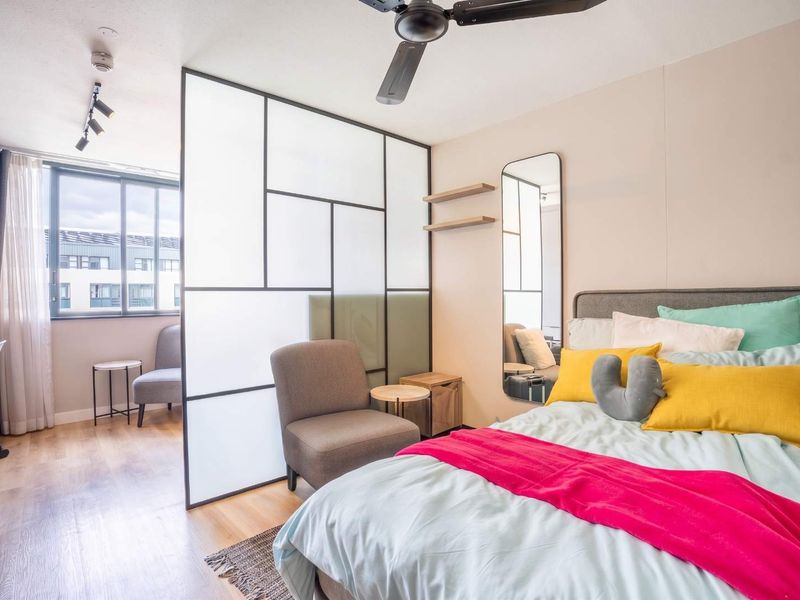Modern bedroom featuring a stylish frosted glass room divider, ceiling fan, track lighting, and laminate flooring, creating a bright and contemporary living space.
