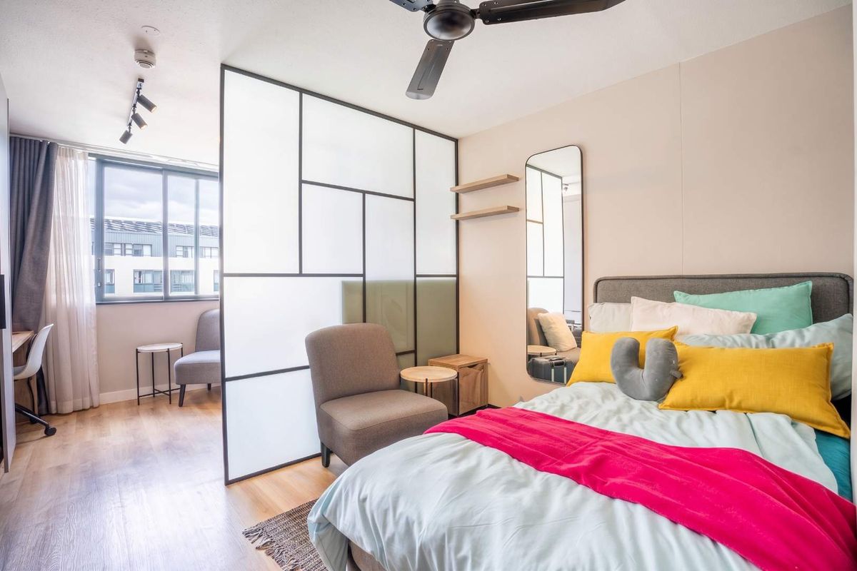 Modern bedroom featuring a stylish frosted glass room divider, ceiling fan, track lighting, and laminate flooring, creating a bright and contemporary living space.