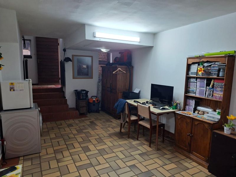 A multi-purpose utility space featuring durable tiled flooring, a staircase leading to an upper level, and functional overhead lighting.