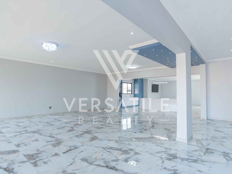 Spacious open-plan living area featuring polished marble-look floor tiles, modern recessed ceiling lighting, and a clean, neutral aesthetic.