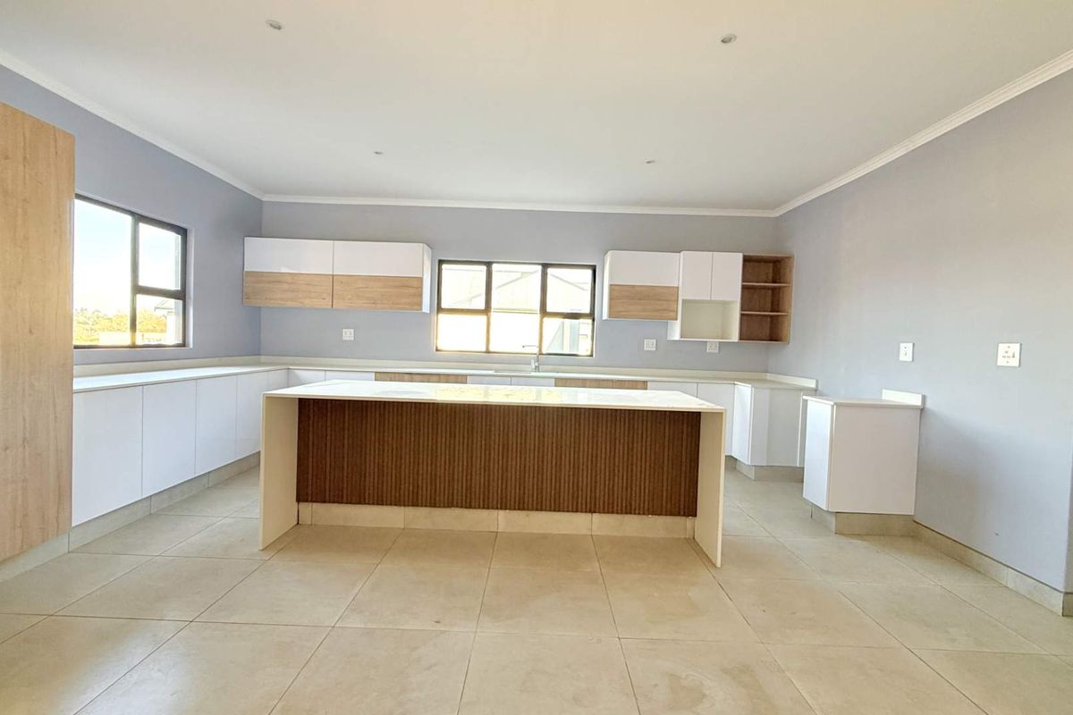 Modern, spacious kitchen featuring a central island, ample cabinetry, and tiled flooring, offering a clean and functional layout.