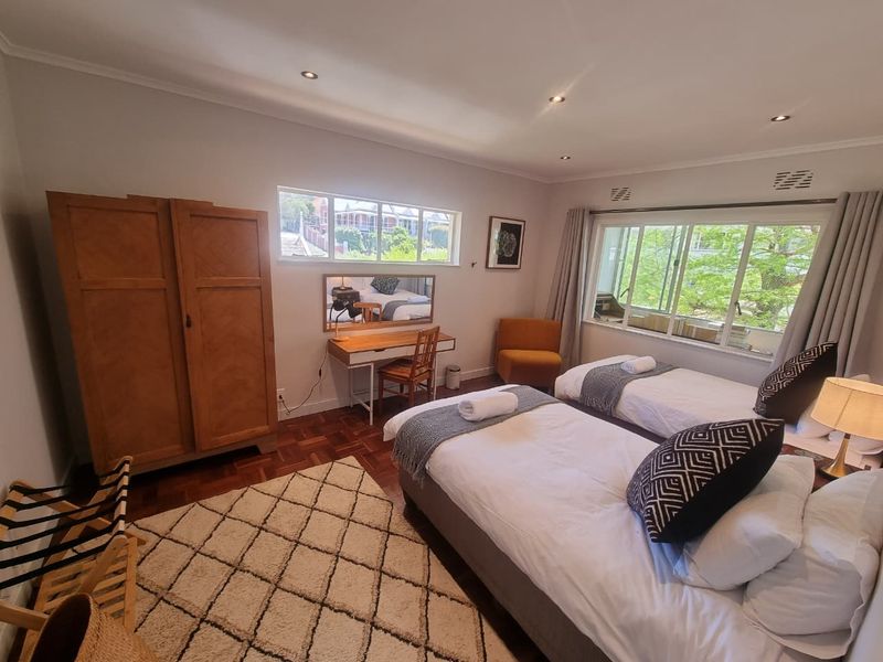 A well-lit bedroom featuring parquet flooring, large windows providing natural light, and recessed ceiling lighting.