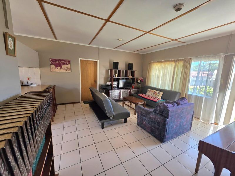 Open-plan living area featuring tiled flooring, a breakfast bar, and direct access to the exterior through a sliding glass door.