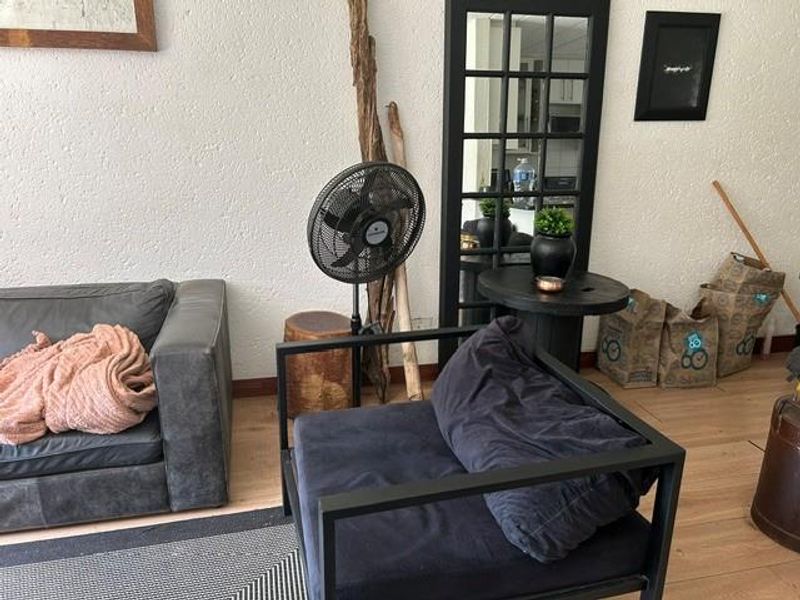 A living room area featuring light-toned laminate flooring and textured walls, providing a neutral base for interior design.
