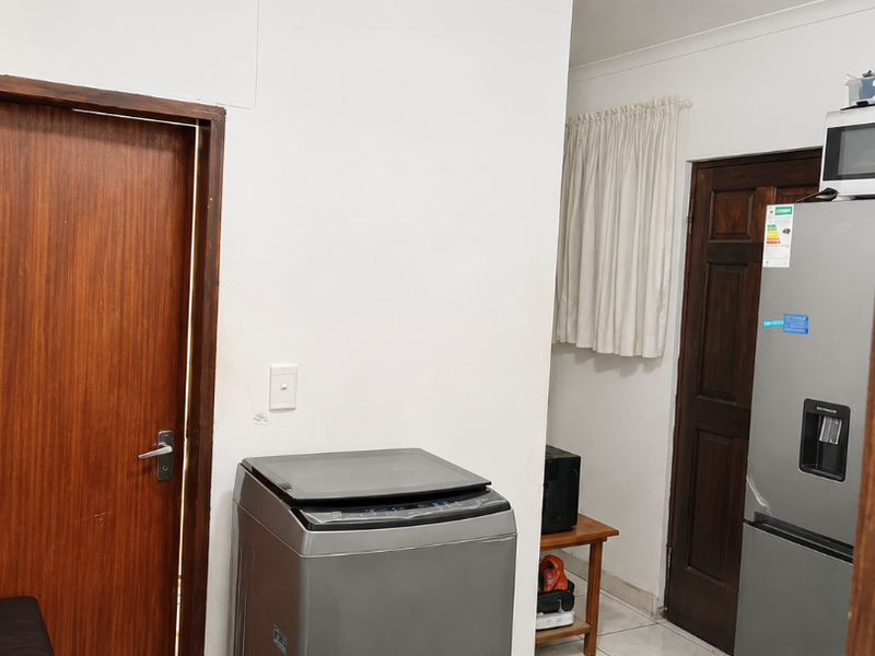 A functional laundry area featuring tiled flooring and solid wood doors, providing access to adjacent rooms.