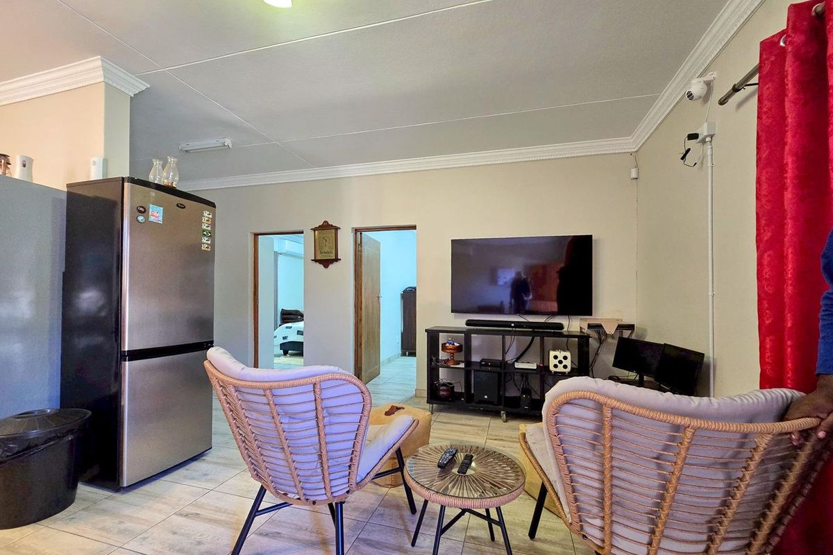 A living area featuring tiled flooring, crown molding, and direct access to adjacent rooms, providing a functional and open layout.