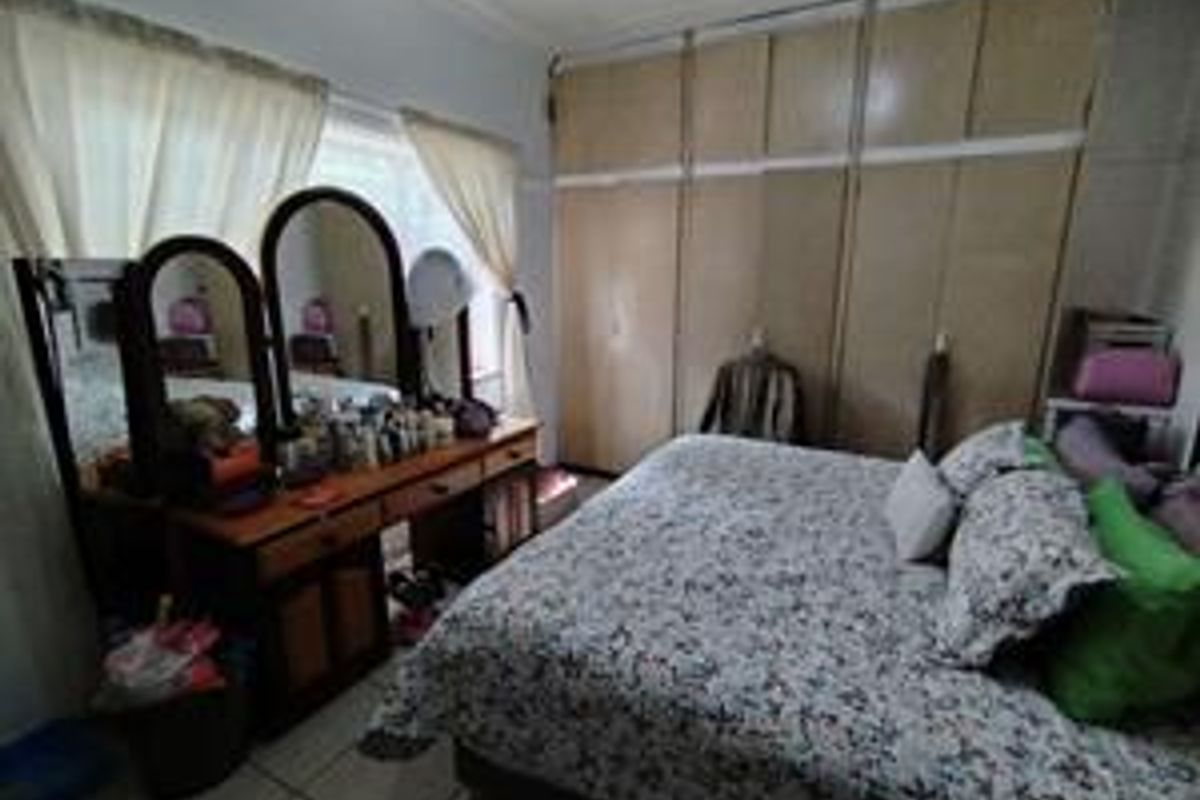 A bedroom featuring built-in floor-to-ceiling wooden wardrobes and tiled flooring, offering ample storage space.