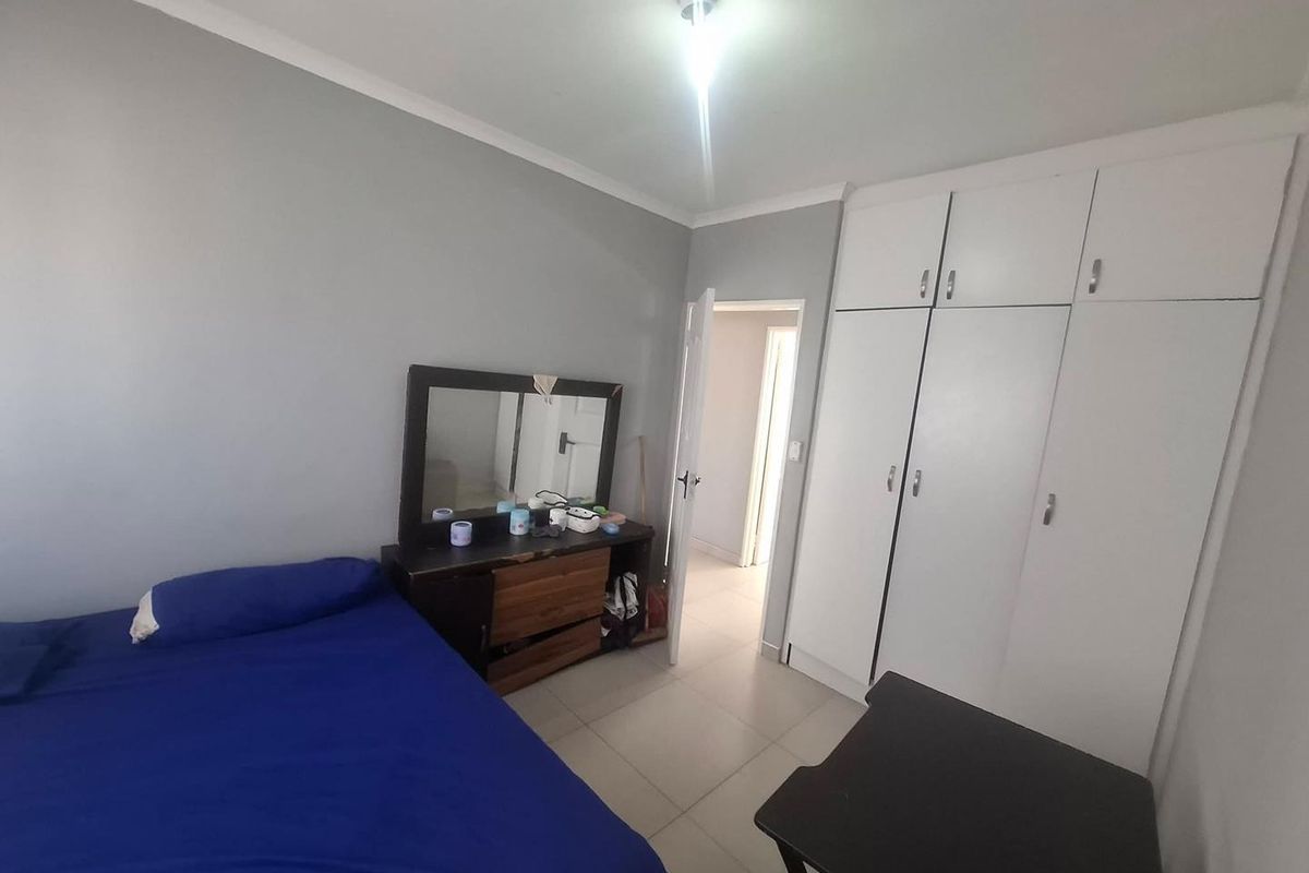 A functional bedroom featuring built-in cupboards, neutral wall finishes, and tiled flooring, providing a practical living space.