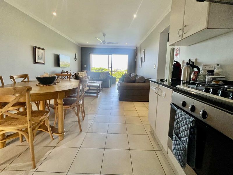 Open-plan living and dining area featuring tiled floors, recessed lighting, and a modern kitchen with a built-in oven and gas hob.