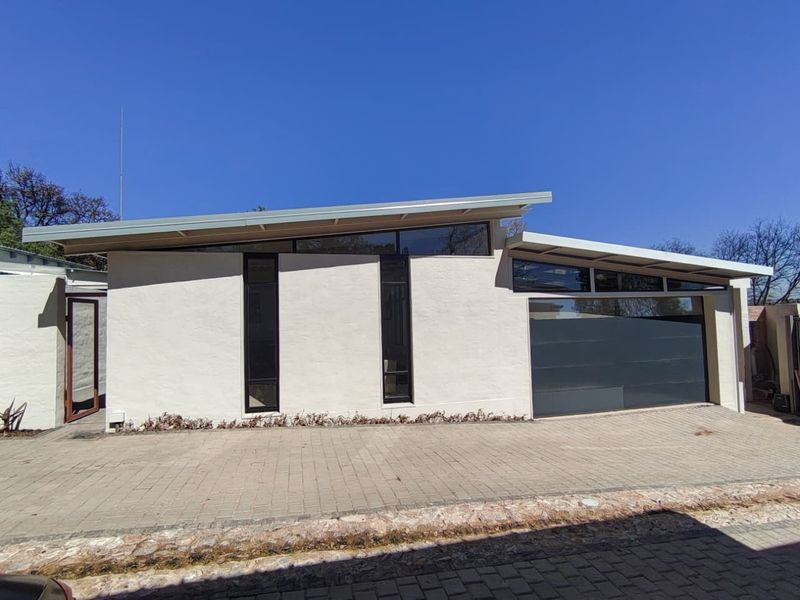 Modern townhouse exterior featuring a distinctive skillion roofline, clerestory windows, a sleek sectional garage door, and a clean paved driveway.