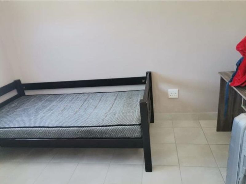 A simple bedroom featuring neutral wall paint and tiled flooring, providing a functional space ready for personalization.