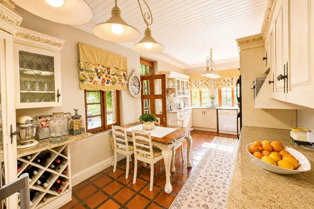 A charming country-style kitchen featuring granite countertops, custom cabinetry with integrated wine storage, and traditional terracotta floor tiles.