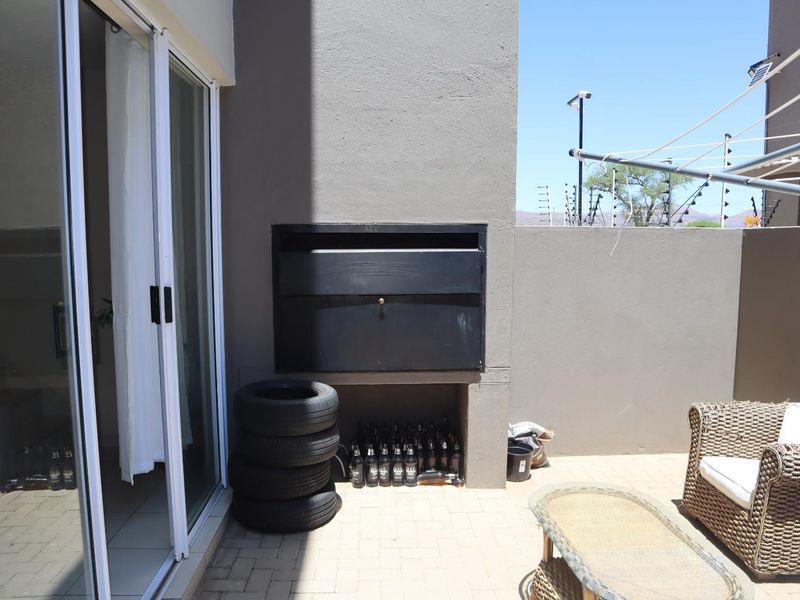 Outdoor patio area featuring a built-in braai, paved flooring, and direct access to the interior through sliding glass doors.