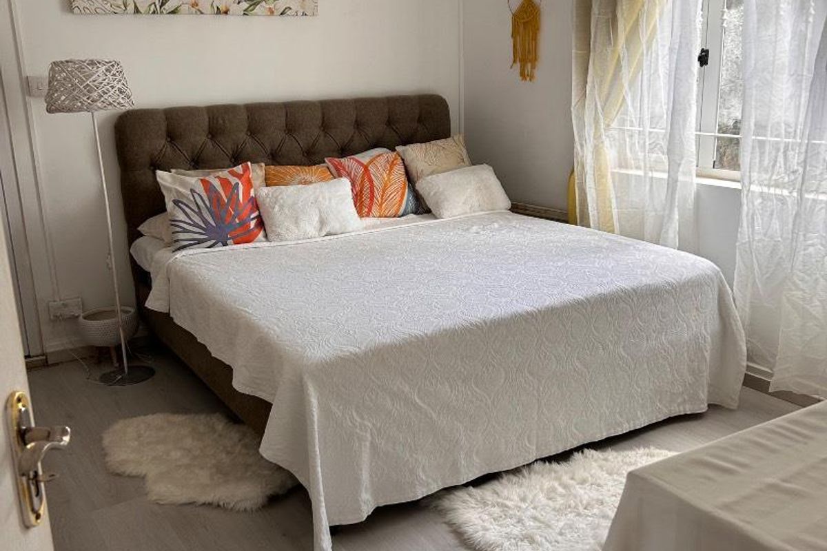 A well-lit bedroom featuring light-toned laminate flooring and a window with natural light, providing a comfortable and functional living space.