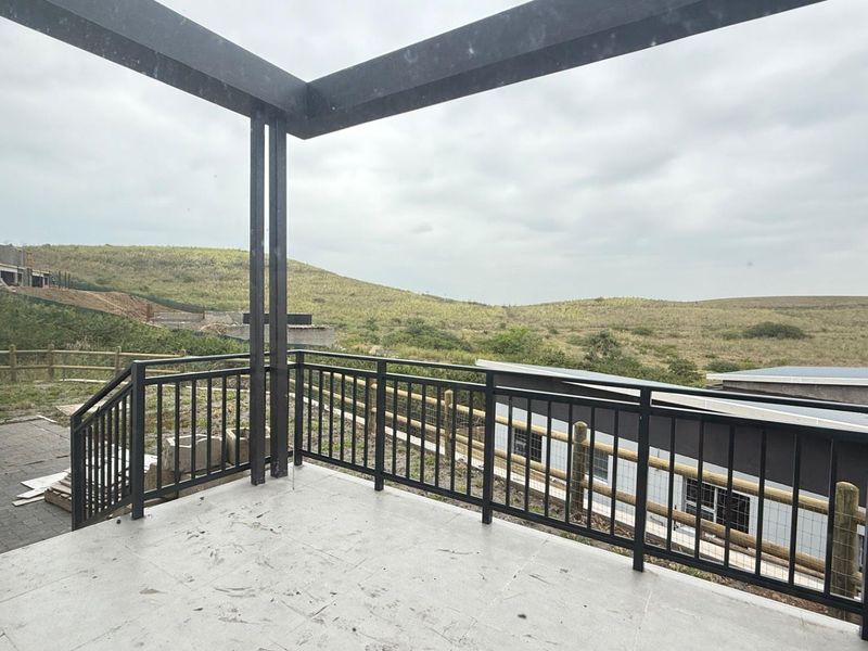 An elevated balcony featuring a modern metal pergola and balustrade, offering expansive views of the surrounding landscape.