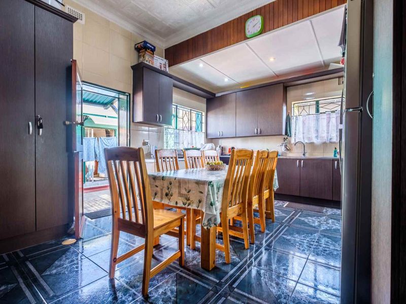 A functional kitchen featuring dark built-in cabinetry, tiled flooring, and direct access to an outdoor area.