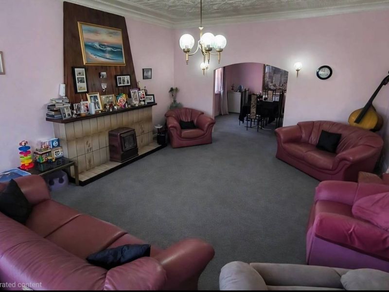 Spacious living room featuring a traditional fireplace with mantelpiece, decorative ceiling rose, and an arched entryway leading to the dining area.