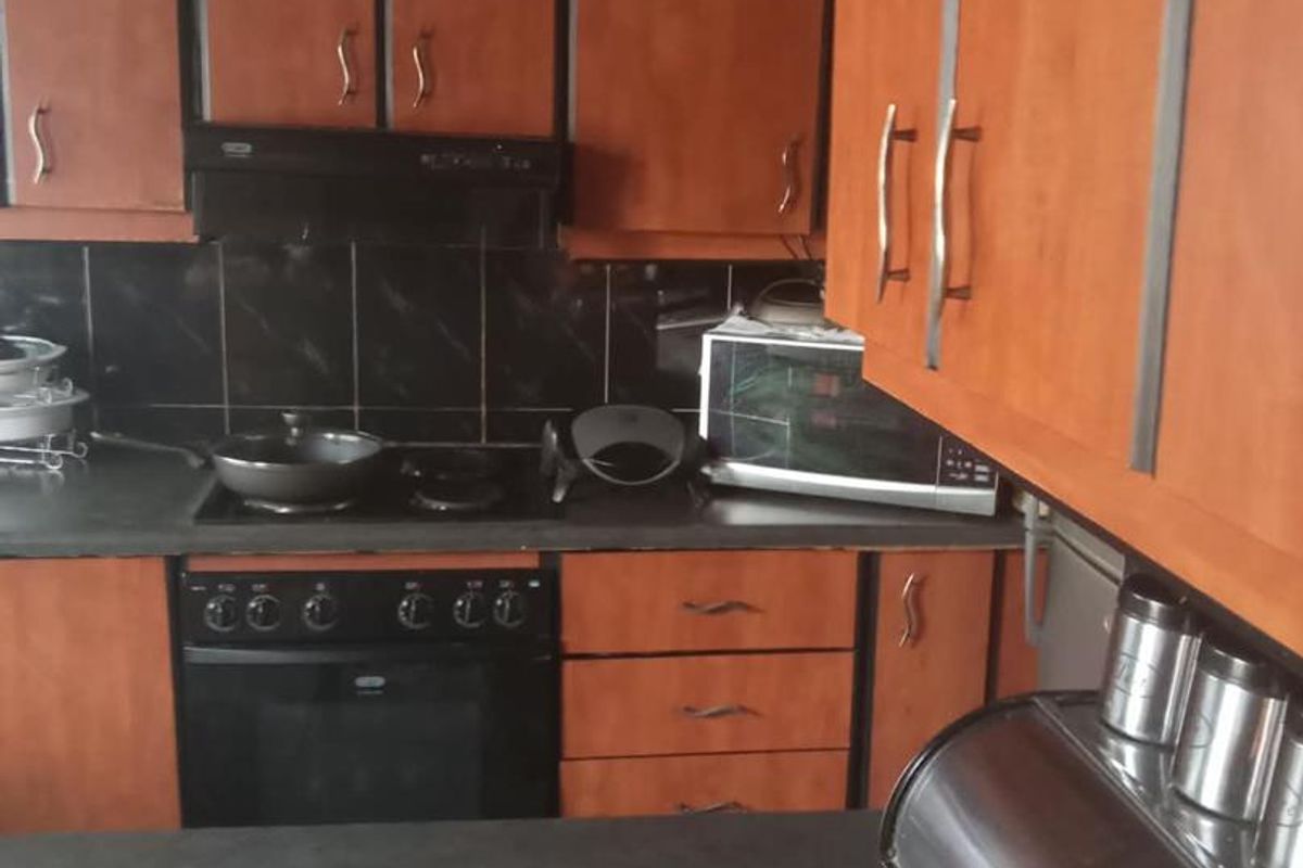 A functional kitchen featuring wood-finish cabinetry, dark countertops, a built-in oven, and a tiled backsplash, offering a practical layout for daily cooking.