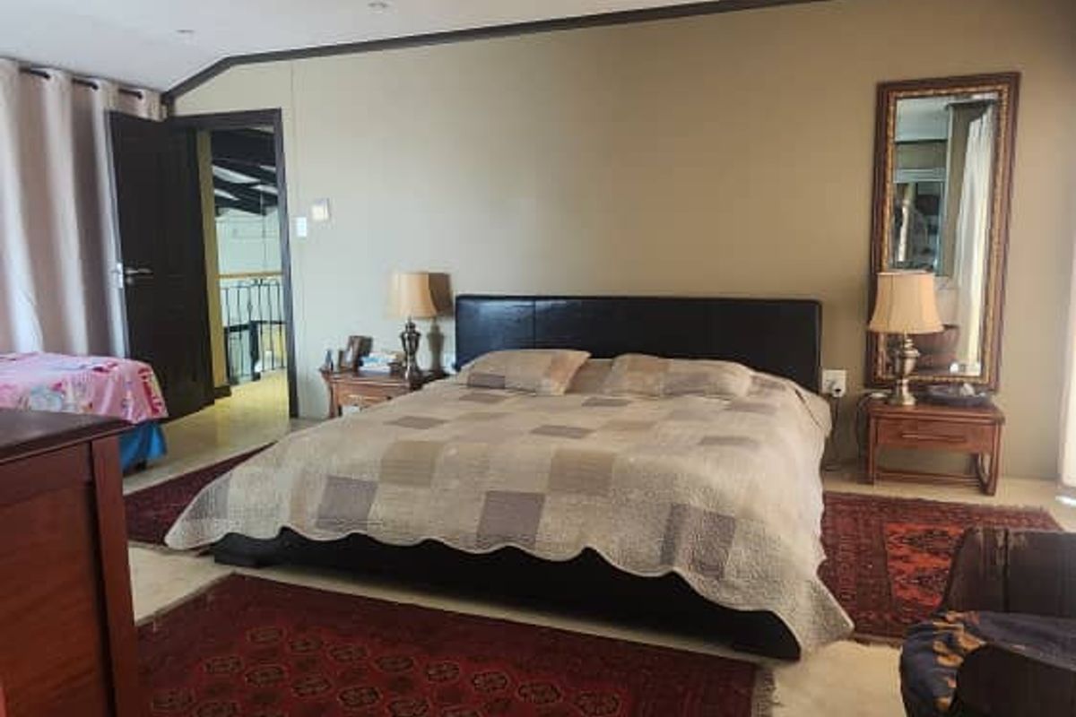 Spacious bedroom featuring a ceiling fan, neutral wall tones, and direct access to an adjacent hallway area.