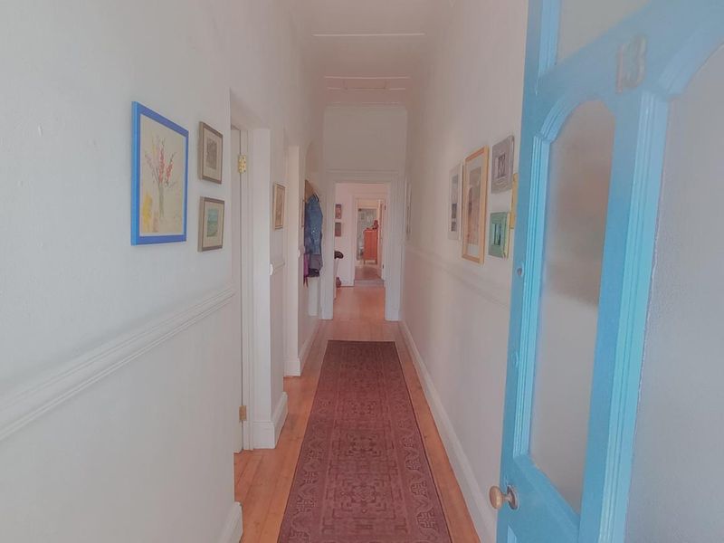 A bright hallway featuring timber flooring, classic picture rails, and white walls, providing access to multiple rooms within the home.