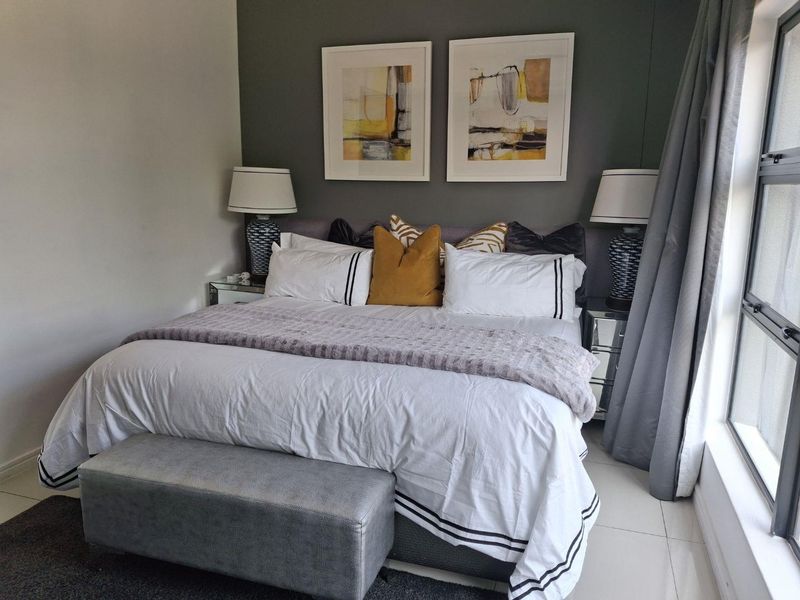 A well-maintained bedroom featuring tiled flooring and a large window, providing a bright and comfortable living space.