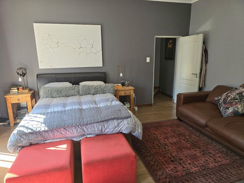 A spacious bedroom featuring dark grey walls, laminate flooring, and an adjoining doorway, providing a comfortable and well-maintained living space.