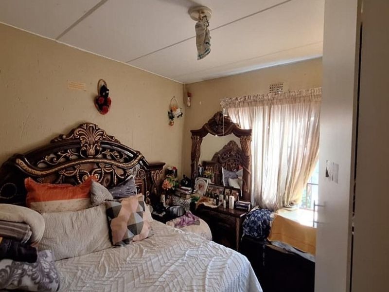 A bedroom featuring a built-in cupboard and curtain rail, currently showing signs of wear including visible ceiling damage.