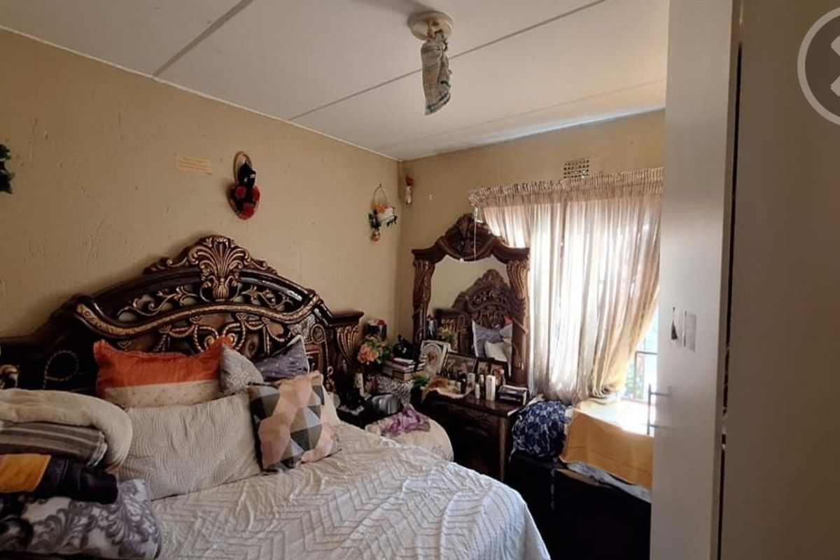 A bedroom featuring a built-in cupboard and curtain rail, currently showing signs of wear including visible ceiling damage.