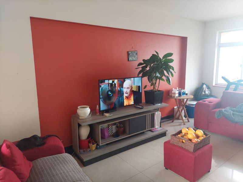 A living room featuring tiled flooring and a prominent red accent wall, providing a functional space for relaxation and entertainment.