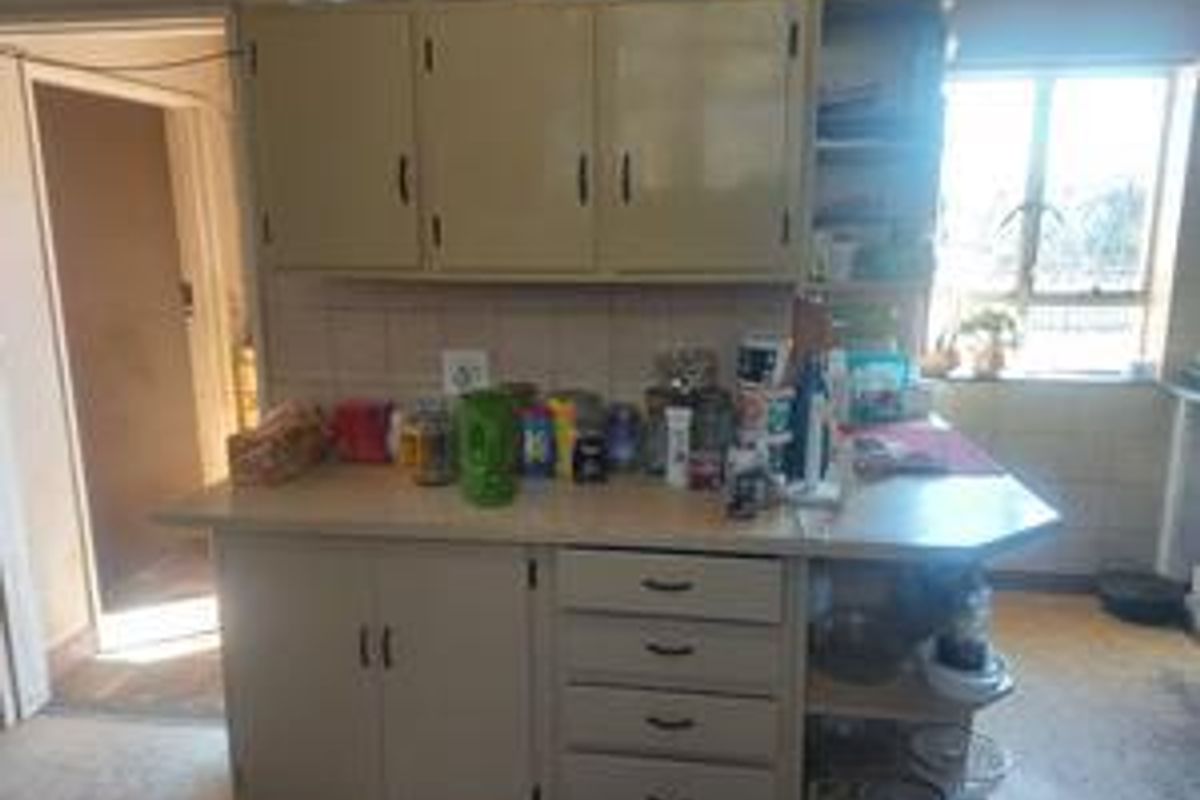 A functional kitchen area featuring dated built-in cabinetry, a tiled backsplash, and ample counter space, providing a practical foundation for future renovation.