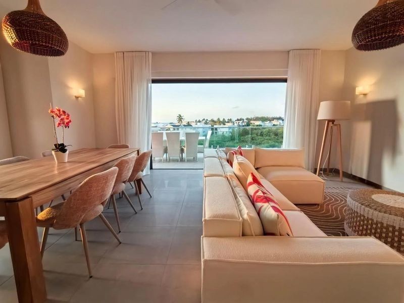 Spacious open-plan living and dining area featuring large sliding glass doors that open onto a balcony with scenic views.