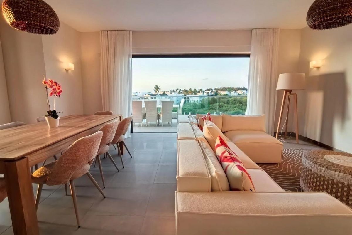 Spacious open-plan living and dining area featuring large sliding glass doors that open onto a balcony with scenic views.