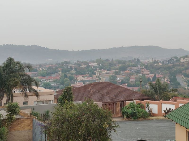 An elevated view overlooking a suburban residential neighbourhood with rolling hills in the background.