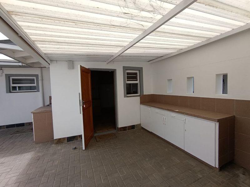 Covered outdoor patio area featuring built-in cabinetry with tiled countertops, paved flooring, and direct access to the interior.