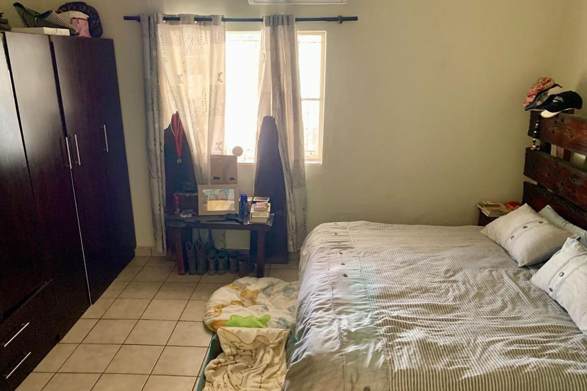 A functional bedroom featuring tiled flooring, a built-in wardrobe, and a wall-mounted air conditioning unit.