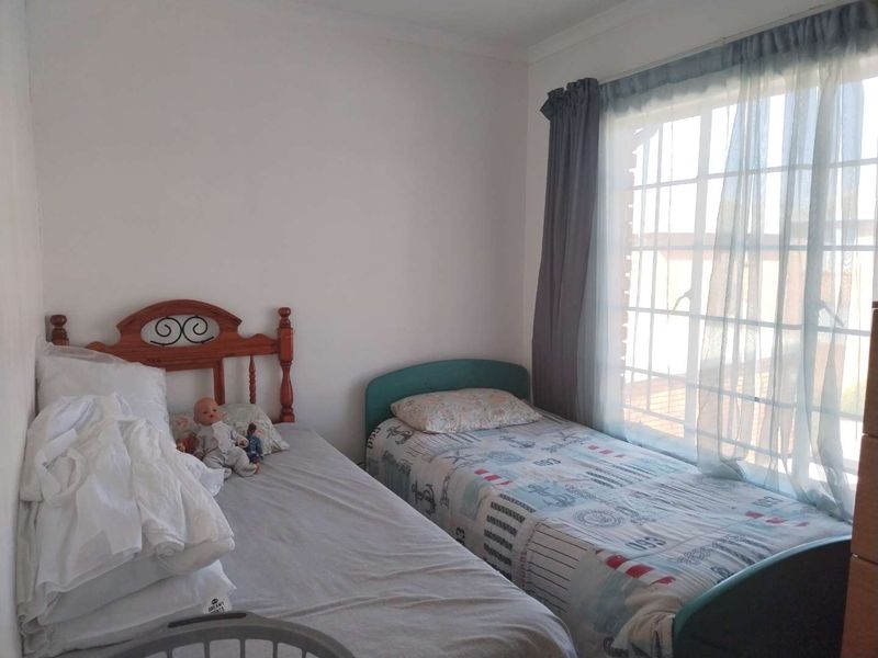 A functional bedroom featuring a large window with security bars and curtain rails, providing natural light to the space.