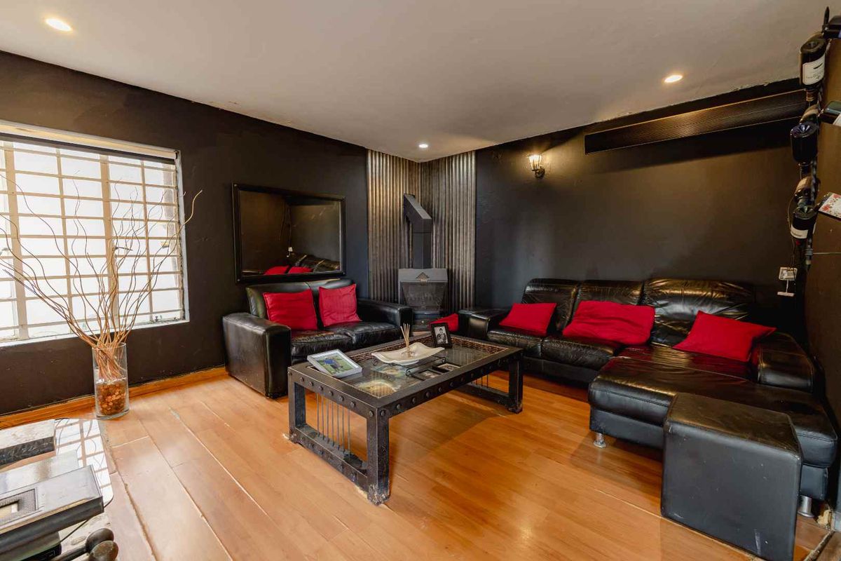 A living room featuring dark walls, wood flooring, and a corner fireplace with metal accent cladding.