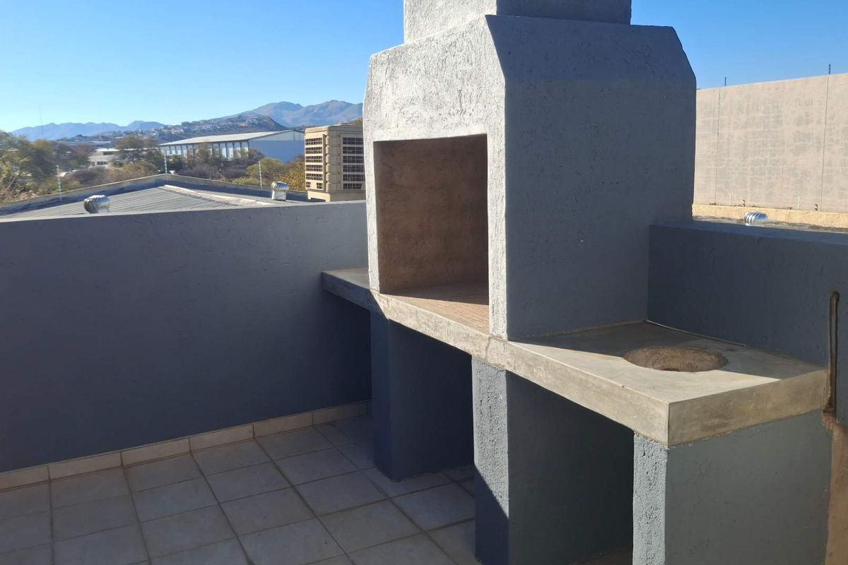 An outdoor balcony area featuring a built-in concrete braai and countertop, offering elevated views of the surrounding industrial landscape.