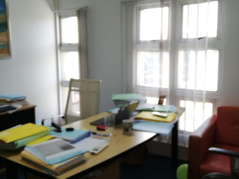 A functional office space featuring large multi-pane windows for natural light and a wall-mounted air conditioning unit.