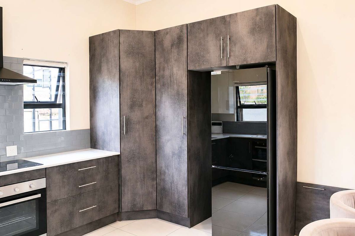 Modern kitchen featuring dark textured cabinetry, subway tile backsplash, built-in oven, electric hob, and an integrated fridge housing unit.