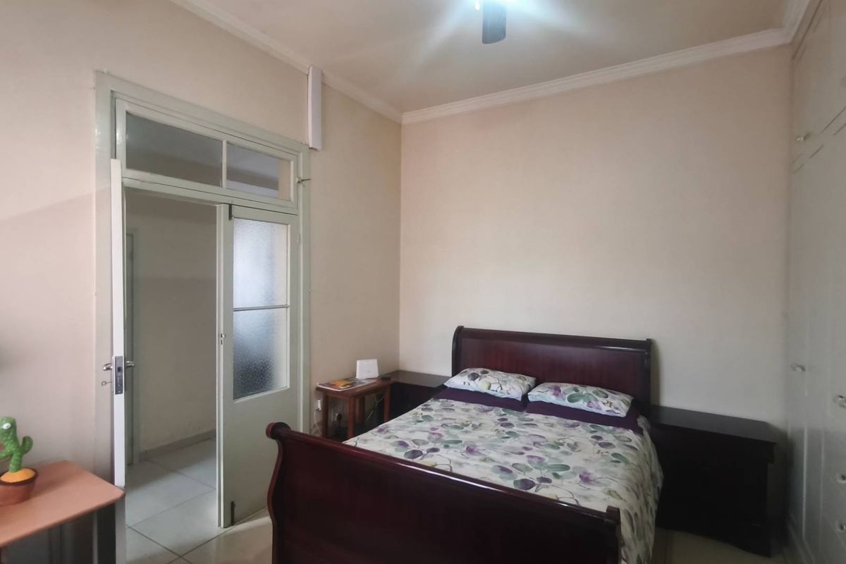 A bedroom featuring built-in wardrobes, a ceiling fan, and a classic transom door leading to an adjacent space.