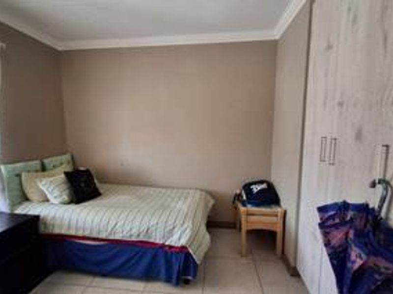 A functional bedroom featuring built-in cupboards, neutral wall tones, and tiled flooring, providing a practical living space.