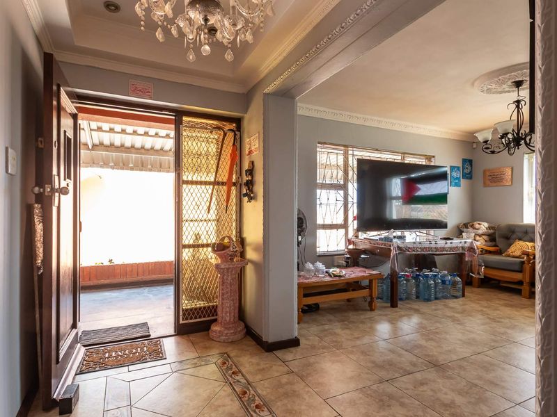 Open-plan living area featuring tiled flooring, decorative ceiling cornices, and direct access to an outdoor patio through a secure entrance.