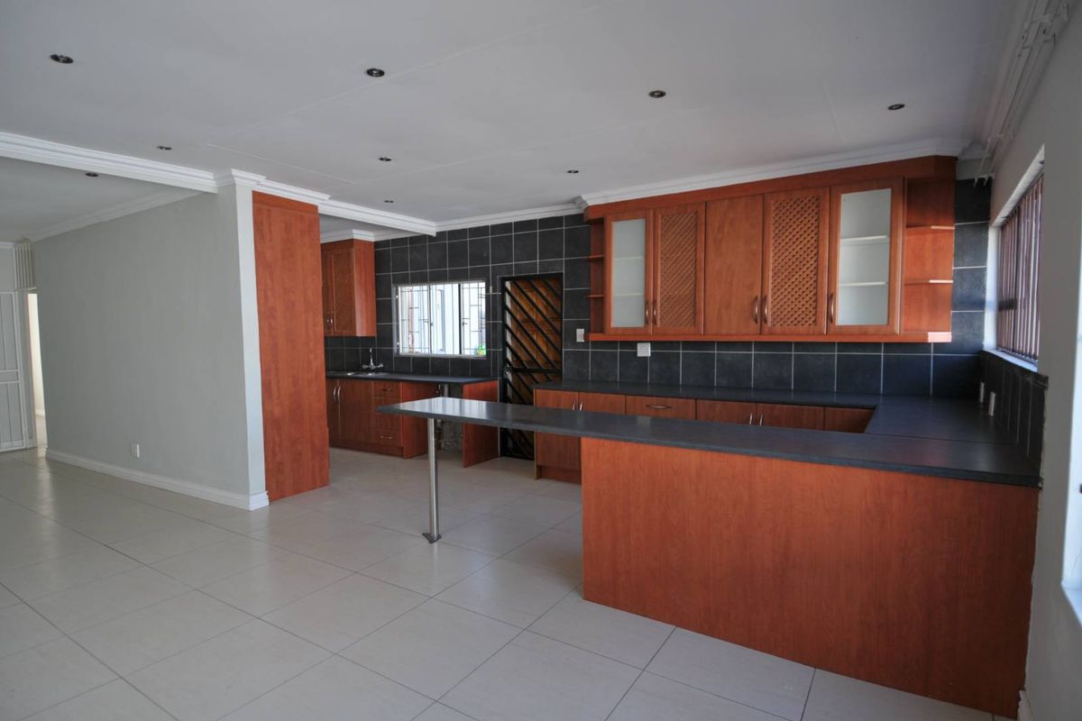 Spacious kitchen featuring wooden cabinetry, dark countertops, a breakfast bar, and tiled flooring, offering a functional layout for meal preparation.