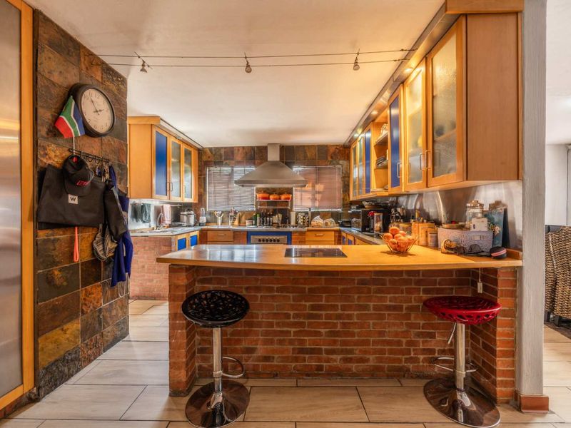 A rustic-style kitchen featuring a brick breakfast bar, wooden countertops, slate wall accents, and built-in cabinetry with integrated appliances.